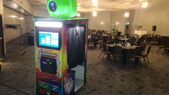 Photo booth set up in a banquet hall with round tables, December 2023