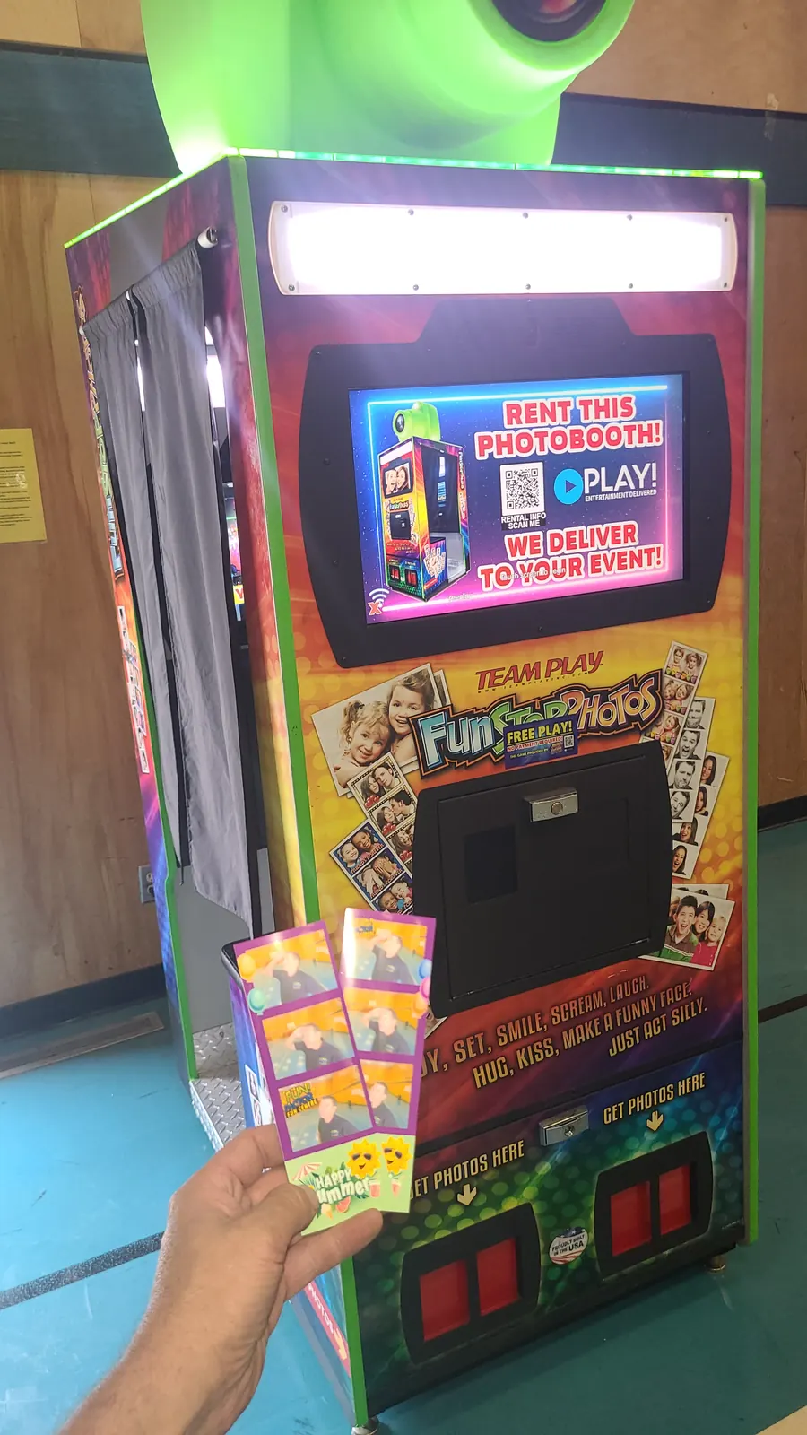 A guest holding freshly printed photo strips beside the booth